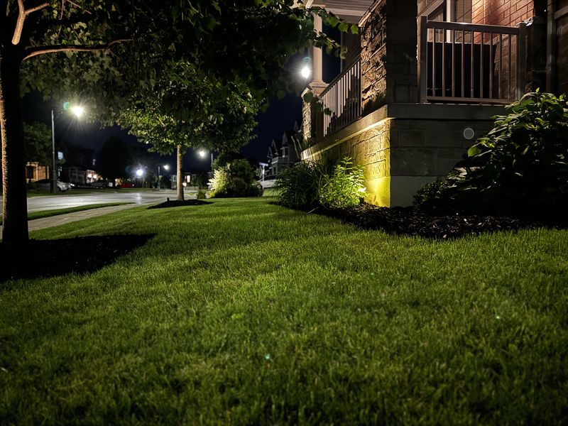 Warm landscape lights on a house and lawn at night